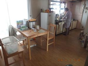 a woman standing in a kitchen with a table at Hirakata-park Guesthouse in Hirakata