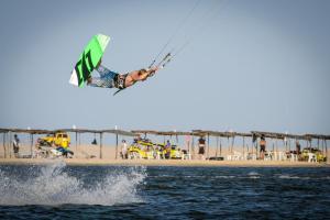 un homme volant à travers l'air alors qu'il fait du kitesurf au-dessus de l'eau dans l'établissement Hotel e Pousada Cumbuco Guesthouse, à Cumbuco