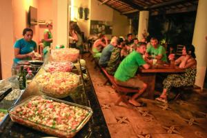 eine Gruppe von Menschen, die an einem Tisch mit Essen sitzen in der Unterkunft Hotel e Pousada Cumbuco Guesthouse in Cumbuco