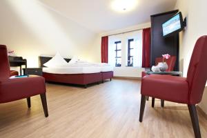 ein Hotelzimmer mit einem Bett, 2 Stühlen und einem TV in der Unterkunft Hotel Altes Gasthaus Schröer in Westerkappeln