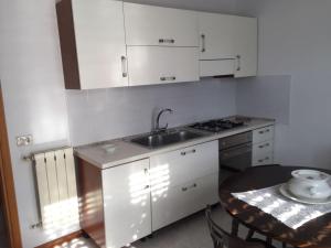 eine Küche mit weißen Schränken, einer Spüle und einem Tisch in der Unterkunft Villa Agata in San Pietro Clarenza