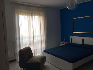ein blaues Schlafzimmer mit einem Bett und einem Stuhl in der Unterkunft Villa Agata in San Pietro Clarenza