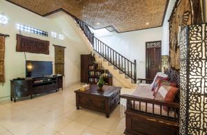 een woonkamer met een bank, een tv en een trap bij Rumah Kelinci in Ubud