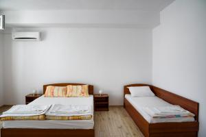 two beds in a room with white walls and wooden floors at Gradina in Chernomorets