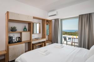 a hotel room with a bed, table, chairs and a window at Glykeria Hotel in Elafonisi