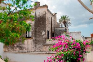 un viejo edificio con flores rosas delante de él en La Corte dei Mille, en Presicce