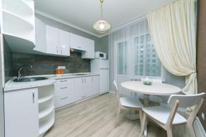 una cucina con armadi bianchi, tavolo e sedie di Sofii Rusovoi 3v a Kiev