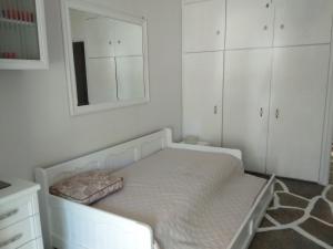 波利克罗诺Maria's beach house的白色卧室配有床和镜子