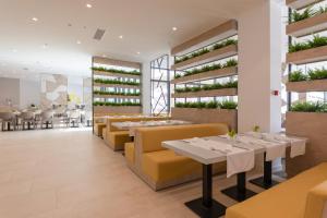 a restaurant with tables and yellow chairs and plants at Apartments Park Plava Laguna in Poreč