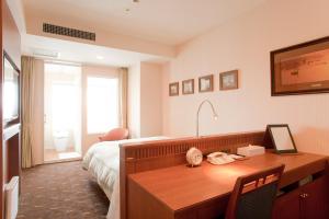 a hotel room with a desk and a bed and a desk at Hotel Boston Plaza Kusatsu in Kusatsu
