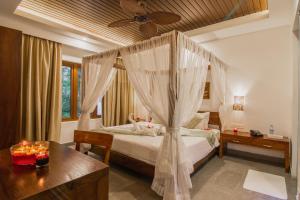 Elixir Hills Suites Resort and Spa في مونار: غرفة نوم بسرير مع ناموسية