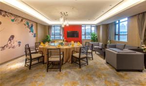 uma sala de jantar com uma mesa e cadeiras e um sofá em Wuhan Hongguang Hotel em Wuhan