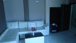 a living room with a white couch with a vase of flowers at Hotel Leder in Kočani