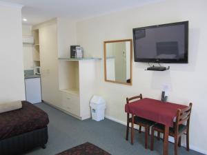 um quarto com uma mesa e uma televisão na parede em Snowgum Motel em Mount Beauty