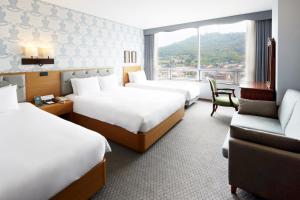 Migliore Hotel Seoul Myeongdong في سول: غرفة فندقية بثلاث اسرة واريكة