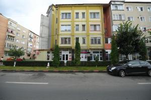 a black car parked in front of a yellow building at Apartament TRIDENT 2 in Haţeg +1 photo
