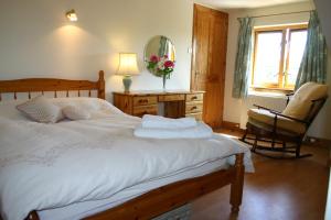 a bedroom with a bed and a chair and a mirror at Garden Cottage in Prestwick