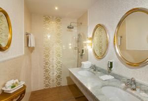 ein Bad mit 2 Waschbecken und einer Dusche mit Spiegeln in der Unterkunft Parkhotel Graz - Traditional Luxury in Graz