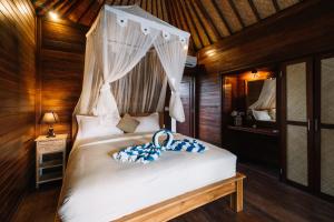 a bedroom with a white bed with a canopy at Dodol Lembongan Cliff Sunset in Nusa Lembongan