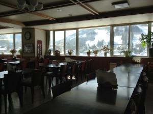 a dining room with tables and chairs and windows at Happokan in Hakuba