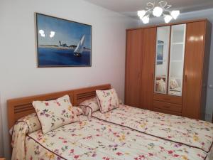 エスカライにあるAPARTAMENTO "PASEO DEL SAÚCO"のベッドルーム1室(ベッド1台付)が備わります。壁には絵画が飾られています。