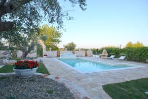a swimming pool in a yard with flowers in a pot at Trulli Petra Chiara in Locorotondo