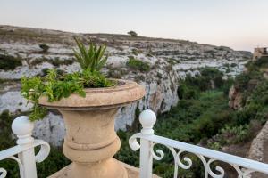 a stone vase with a plant in it on a balcony at Cesca's Boutique Hotel in Xlendi