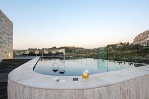 two glasses of wine sitting on a ledge next to a swimming pool at Cesca's Boutique Hotel in Xlendi