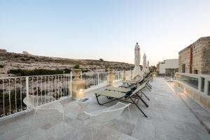 a patio with chairs and umbrellas on a balcony at Cesca's Boutique Hotel in Xlendi