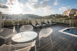 a deck with chairs and tables and a swimming pool at Cesca's Boutique Hotel in Xlendi