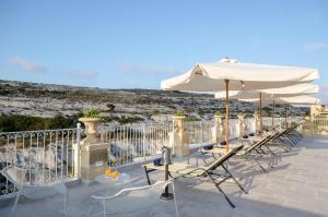 a row of chairs and umbrellas on a patio at Cesca's Boutique Hotel in Xlendi