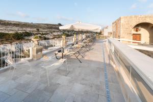a patio with chairs and an umbrella on a roof at Cesca's Boutique Hotel in Xlendi