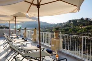 a row of chairs and umbrellas on a balcony at Cesca's Boutique Hotel in Xlendi