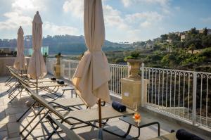 a row of lounge chairs and umbrellas on a balcony at Cesca's Boutique Hotel in Xlendi