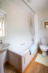 ein Badezimmer mit einer Badewanne, einem WC und einem Waschbecken in der Unterkunft Woodcroft Cottage in Ayr
