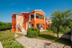 een groot oranje huis met een boom ervoor bij Residence Tanaunella in Budoni