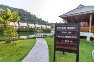 una señal frente a un edificio con un río y una casa en Bhu Tarn Koh Chang Resort & Spa en Ko Chang