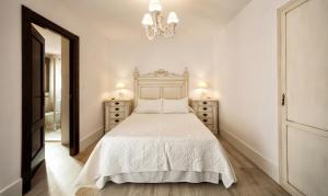 a white bedroom with a bed and two night stands at Nuevo Monteftur in Montefrío