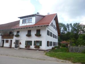 uma casa branca com um telhado vermelho e janelas em Ferienwohnung auf dem Lechsberg em Fuchstal