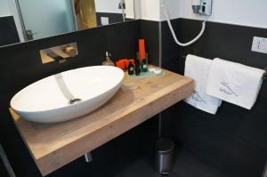 un bagno con lavandino bianco su un bancone in legno di B&B Capo Torre Resort & SPA ad Albisola Superiore
