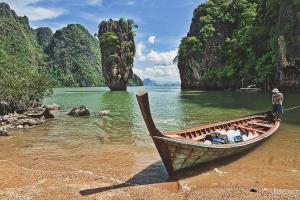 Ein Mann steht auf einem Boot am Strand. in der Unterkunft Thai Muang Resort in Thai Muang