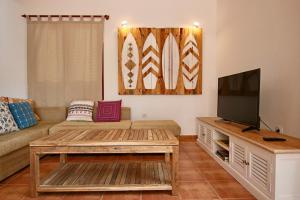 un salon avec un canapé et une télévision dans l'établissement Casa Silencio, Villa with terrace, garden and large pool area, à Corralejo