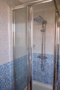une salle de bain avec douche aux carreaux bleus dans l'établissement Casa Silencio, Villa with terrace, garden and large pool area, à Corralejo