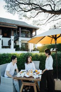 un groupe de personnes assises à une table en train de manger dans l'établissement Na Nirand Romantic Boutique Resort, à Chiang Mai
