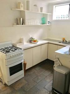 a white kitchen with a stove and a sink at Gorgeous Subiaco cottage in Perth