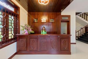 una mujer está de pie detrás de un mostrador de madera en una habitación en Green Hill Villa, en Hoi An