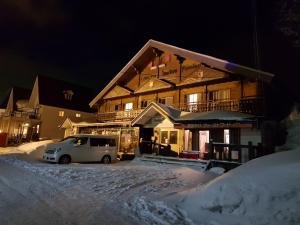 a car parked in front of a house in the snow at Chill Madarao in Iiyama
