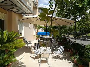 une terrasse avec une table, des chaises et un parasol dans l'établissement Hotel Saturno, à Chianciano Terme