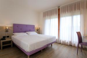 a bedroom with a large bed with a purple headboard at Fantinello Hotel in Caorle