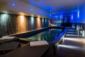 a swimming pool in a hotel with blue lighting at Rock Noir & Spa in La Salle Les Alpes